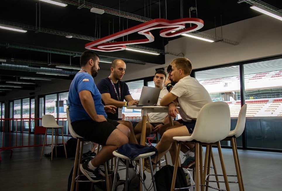 Integrantes del equipo conversando alrededor de una mesa con un portátil
