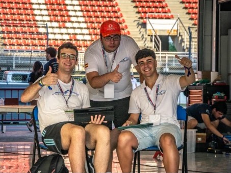 Dos integrantes del equipo sonriendo con el pulgar en alto durante la competición